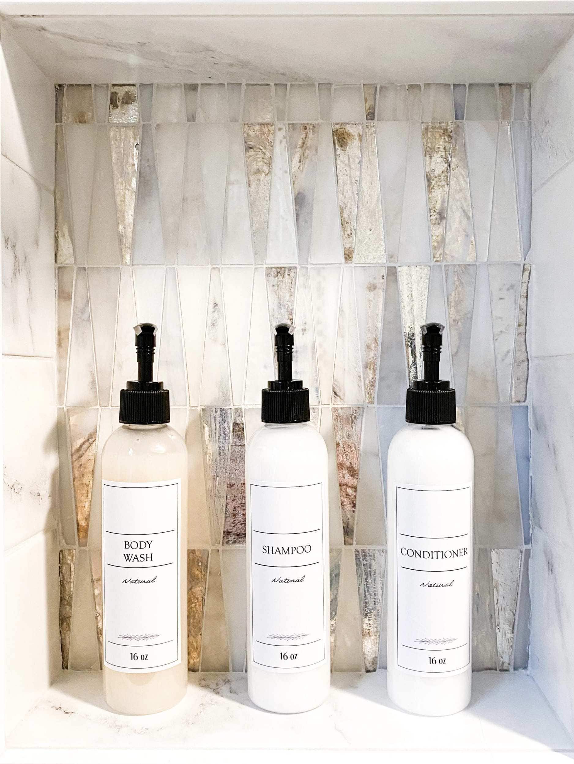 White shampoo bottles with black pumps and a decorative colorful shower niche backsplash