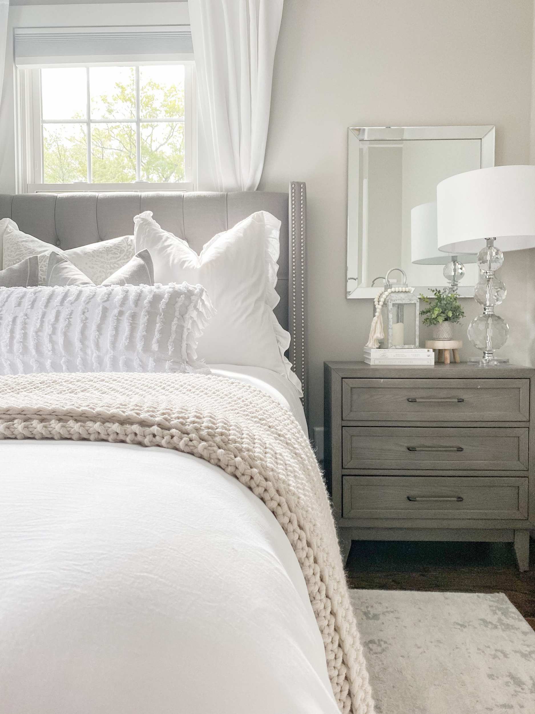 the acorn hill home bedroom with white linens and grey headboard