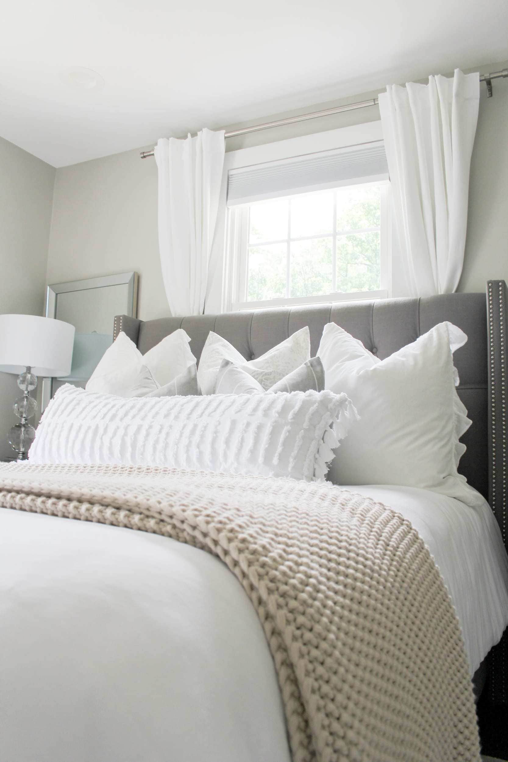 the acorn hill home bedroom with white linens and grey headboard and textured chunky knit blanket