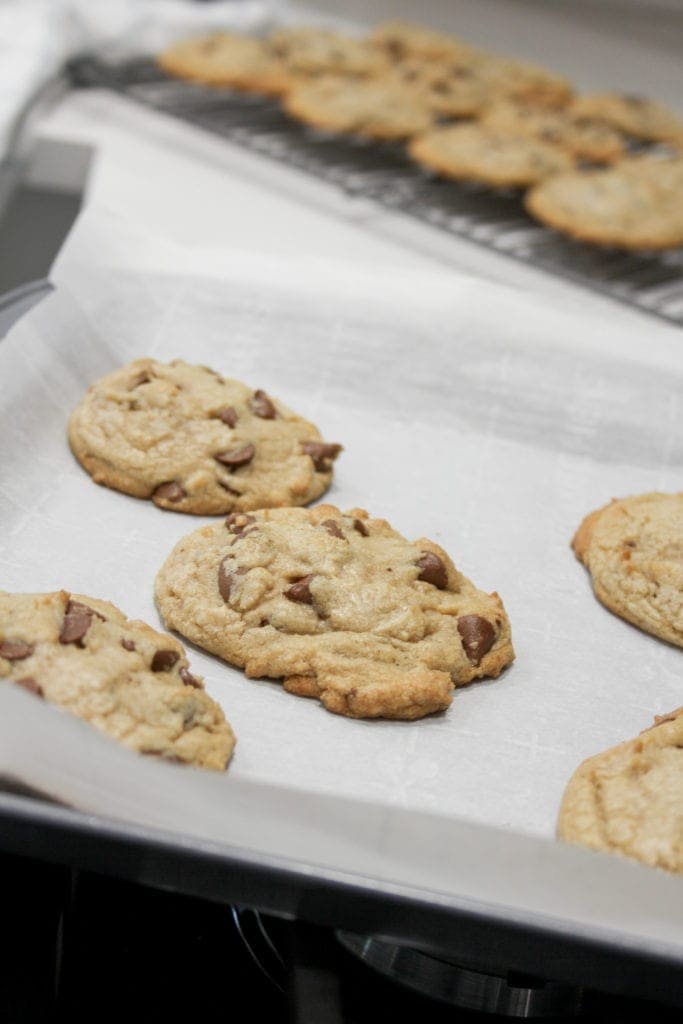 Chocolate chip cookies on parchment paper lined baking sheet. 