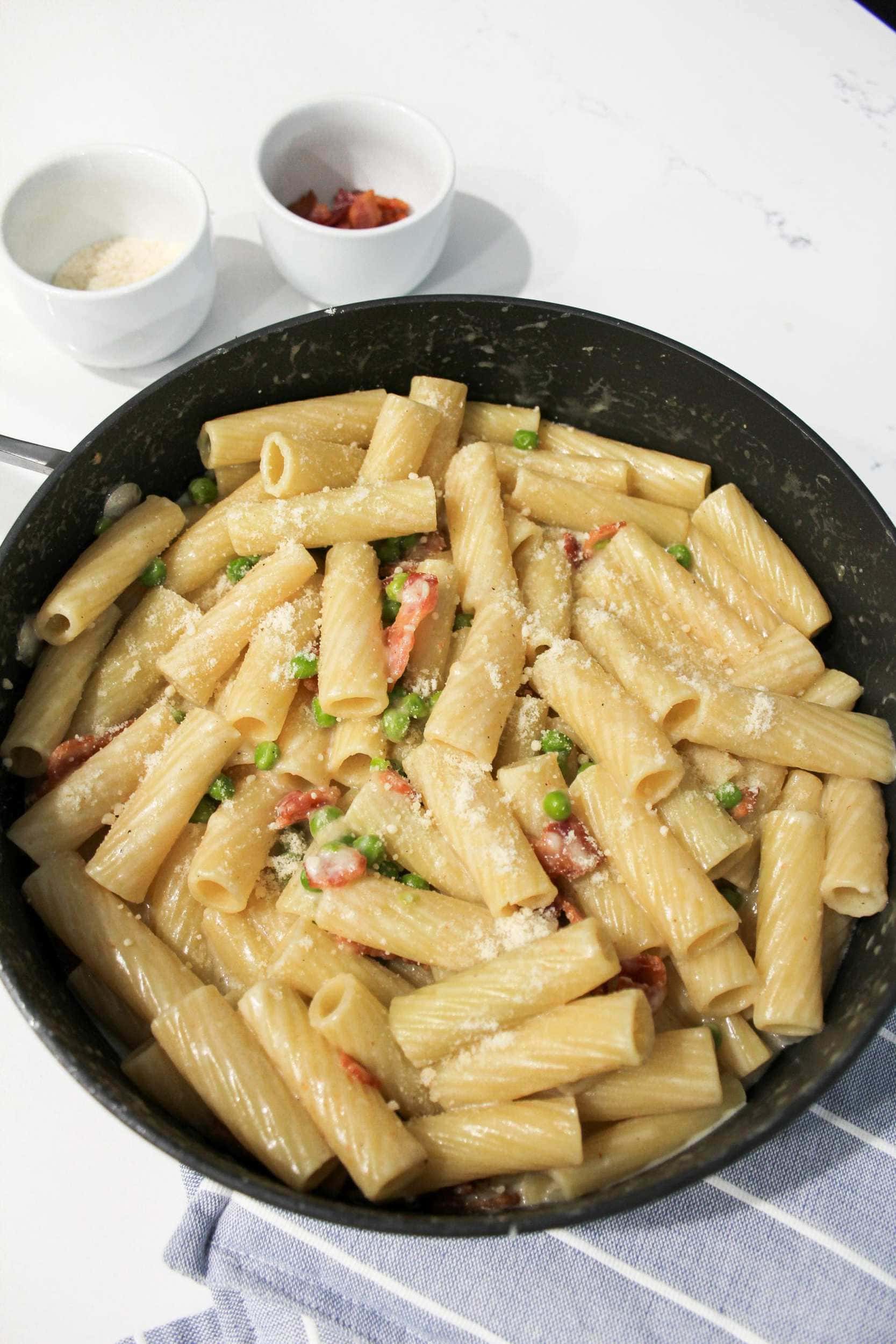 Rigatoni pasta in a light cream sauce with parmesan cheese, bacon, and peas