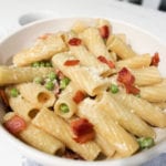 Rigatoni with bacon and peas in a matte white pasta bowl