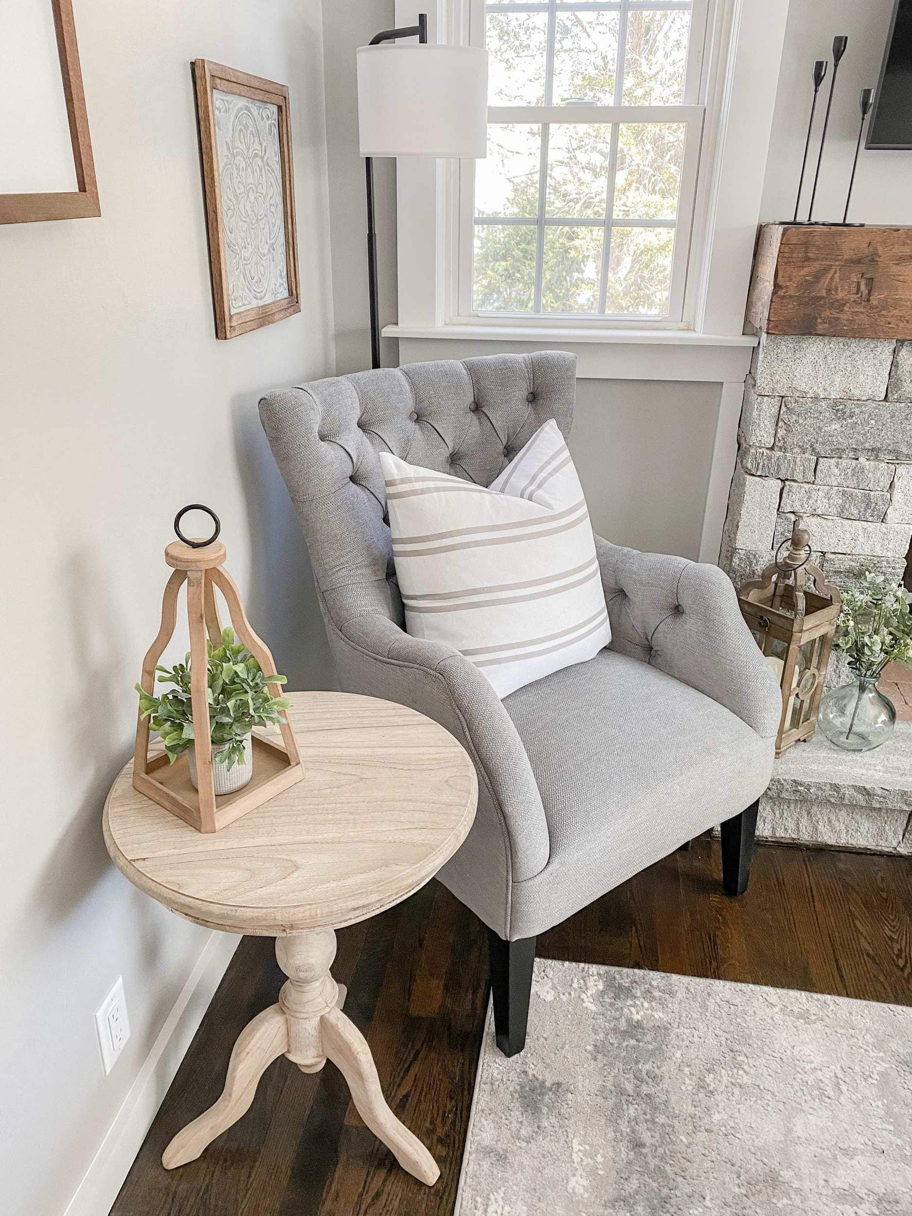 grey tufted armchair, unfinished wood table, lamp, and farmhouse wall decor