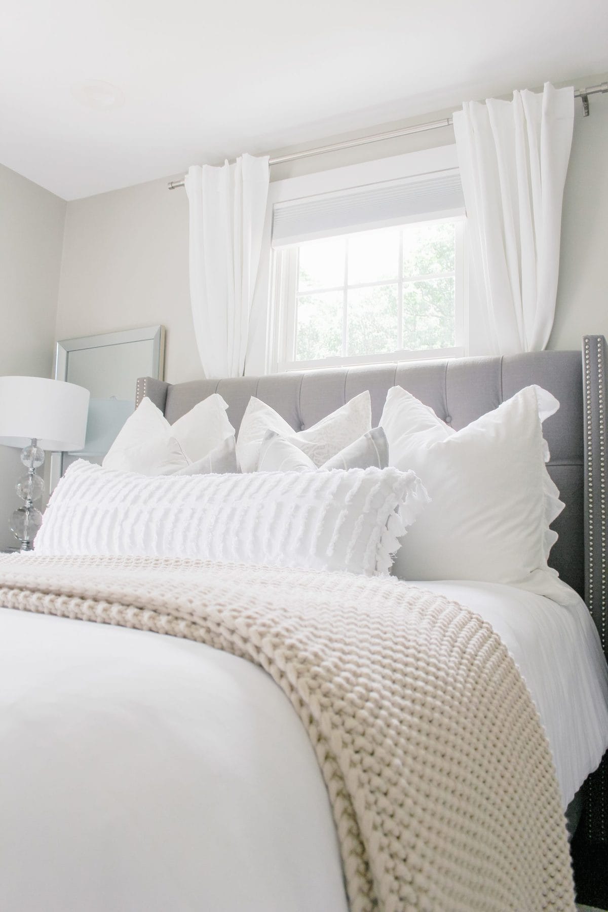 Spring bedroom refresh with light and airy textiles, white bedding, plush pillows, and textured blankets and pillows