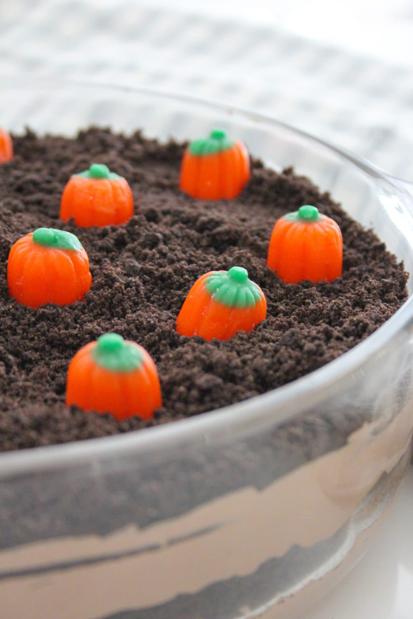 pumpkin patch layered dirt pudding in a clear casserole dish with candy corn pumpkins