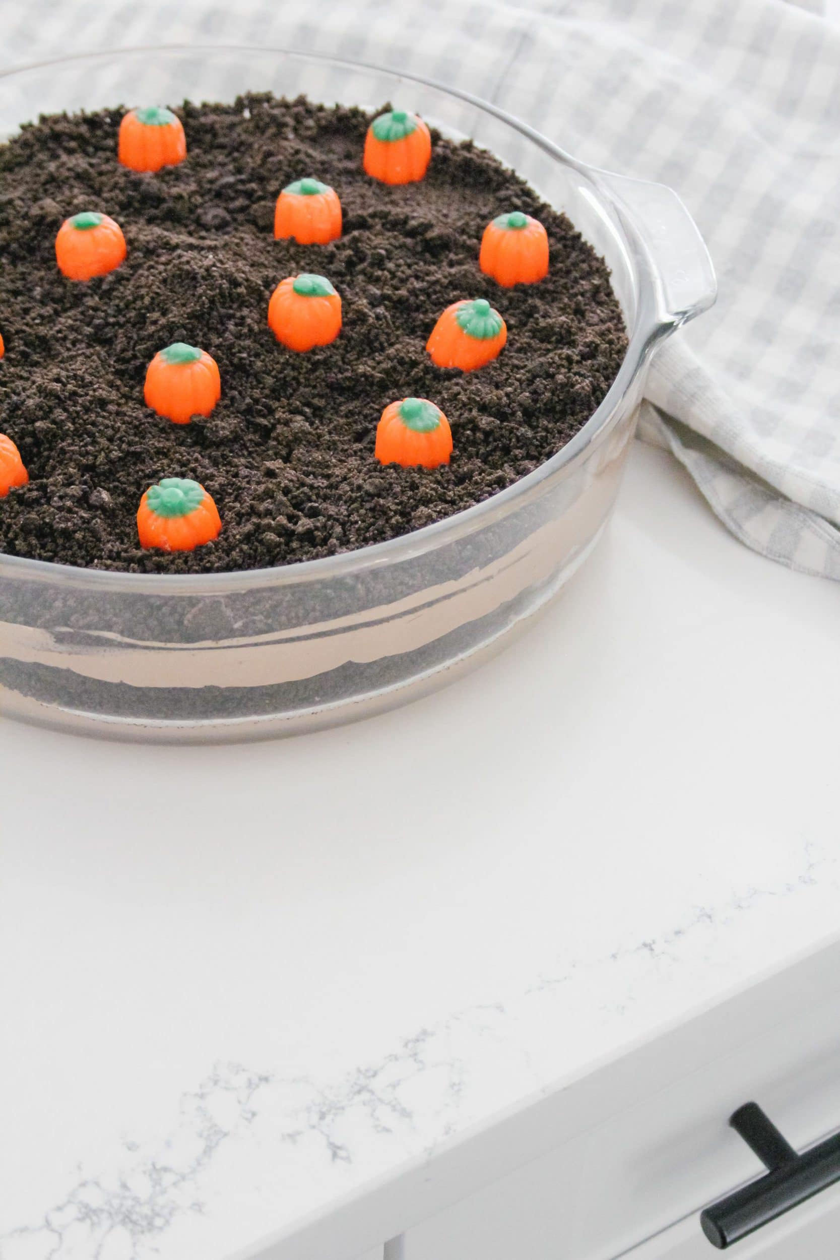 pumpkin patch layered dirt pudding in a clear casserole dish with candy corn pumpkins