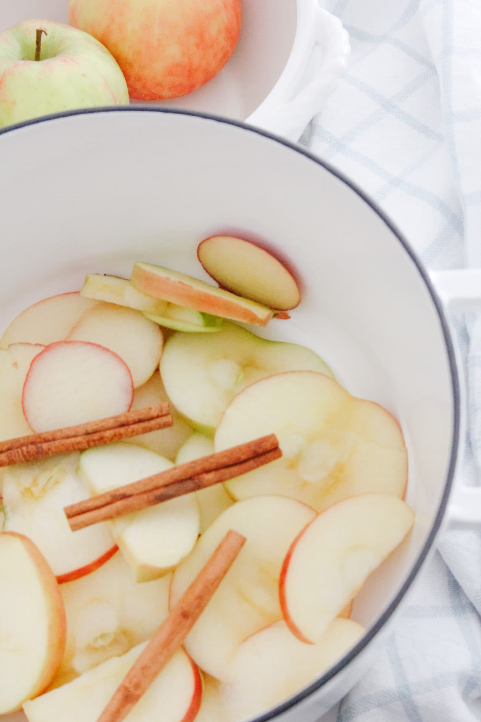 Stovetop apple cinnamon fall potpourri with a fruit bowl filled with apples in a dutch oven. 