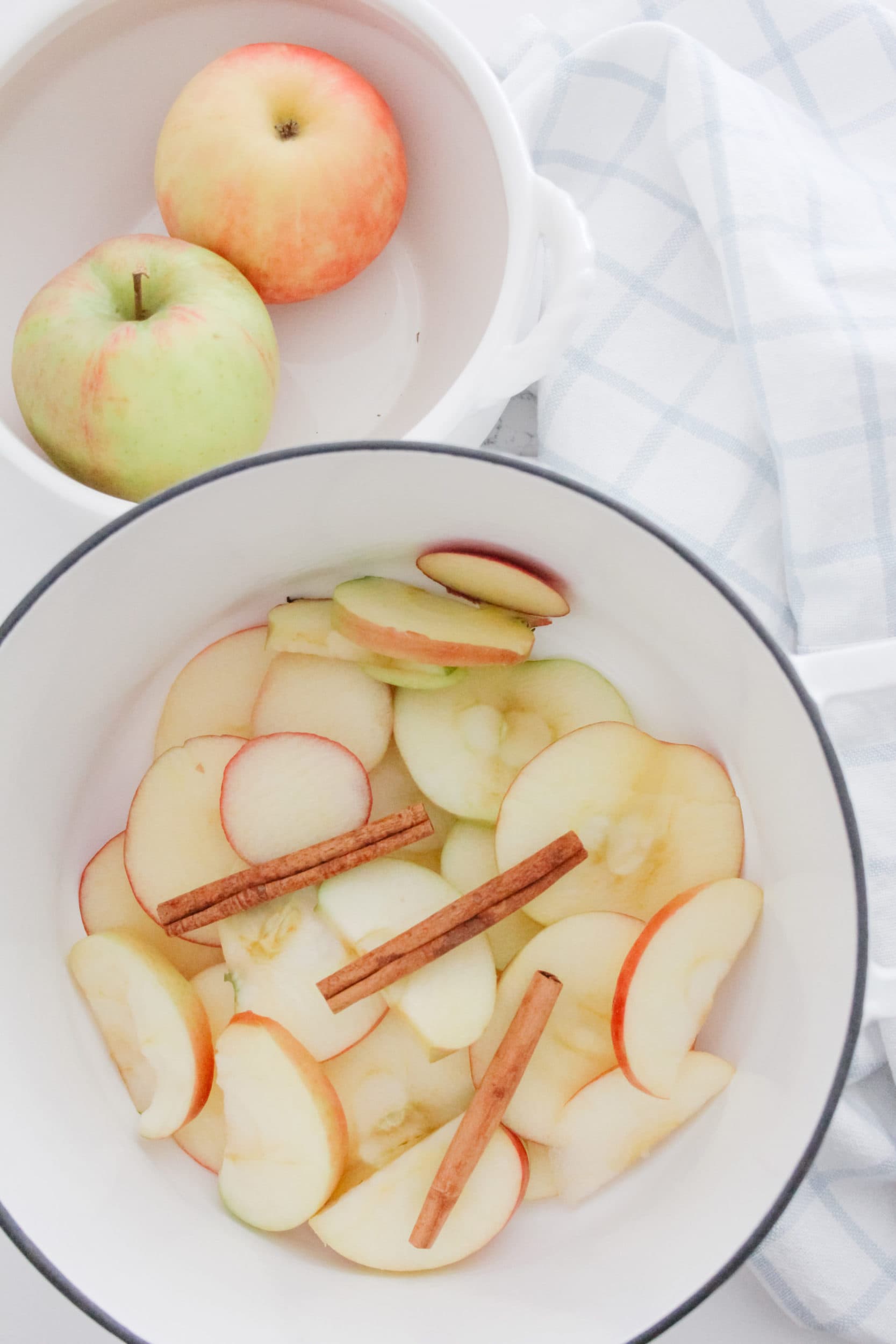 Stovetop apple cinnamon fall potpourri with a fruit bowl filled with apples in a dutch oven. 