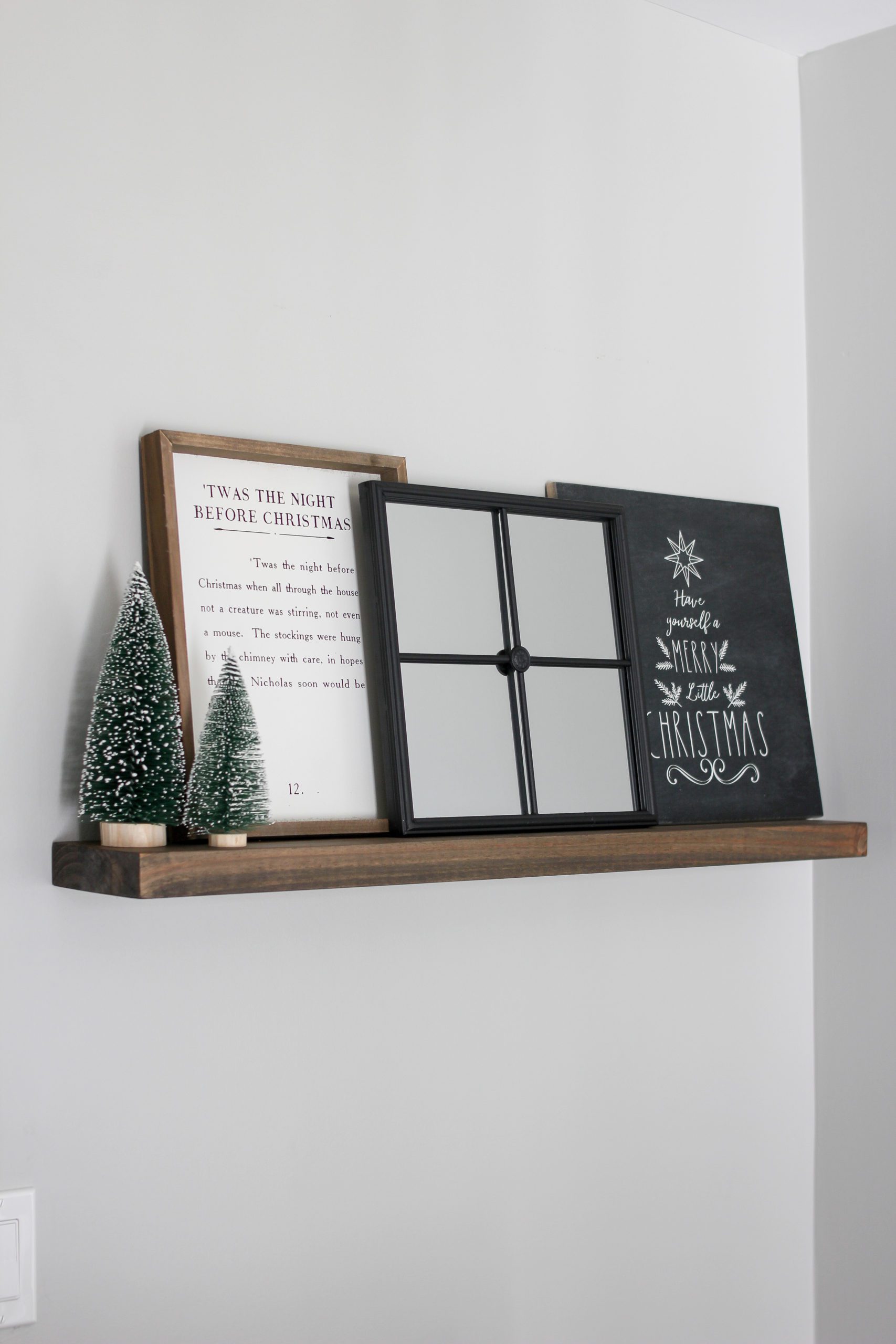 Floating wooden shelf with white flocked bottle brush trees, twas the night before christmas print, farmhouse mirror, and have yourself a merry little christmas print from third & main