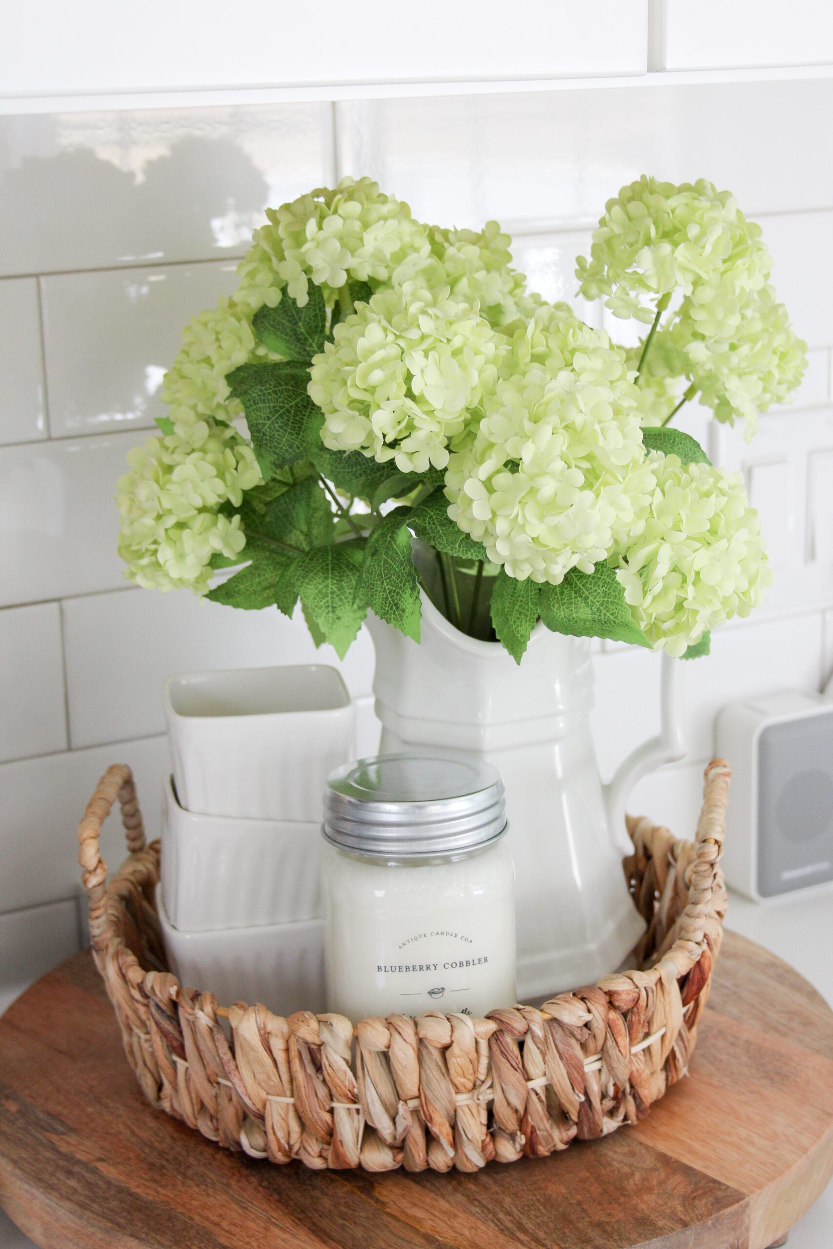 snowball hydrangeas in an ironstone pitcher with scalloped ramekins and a blueberry cobbler in a whicker seagrass basket