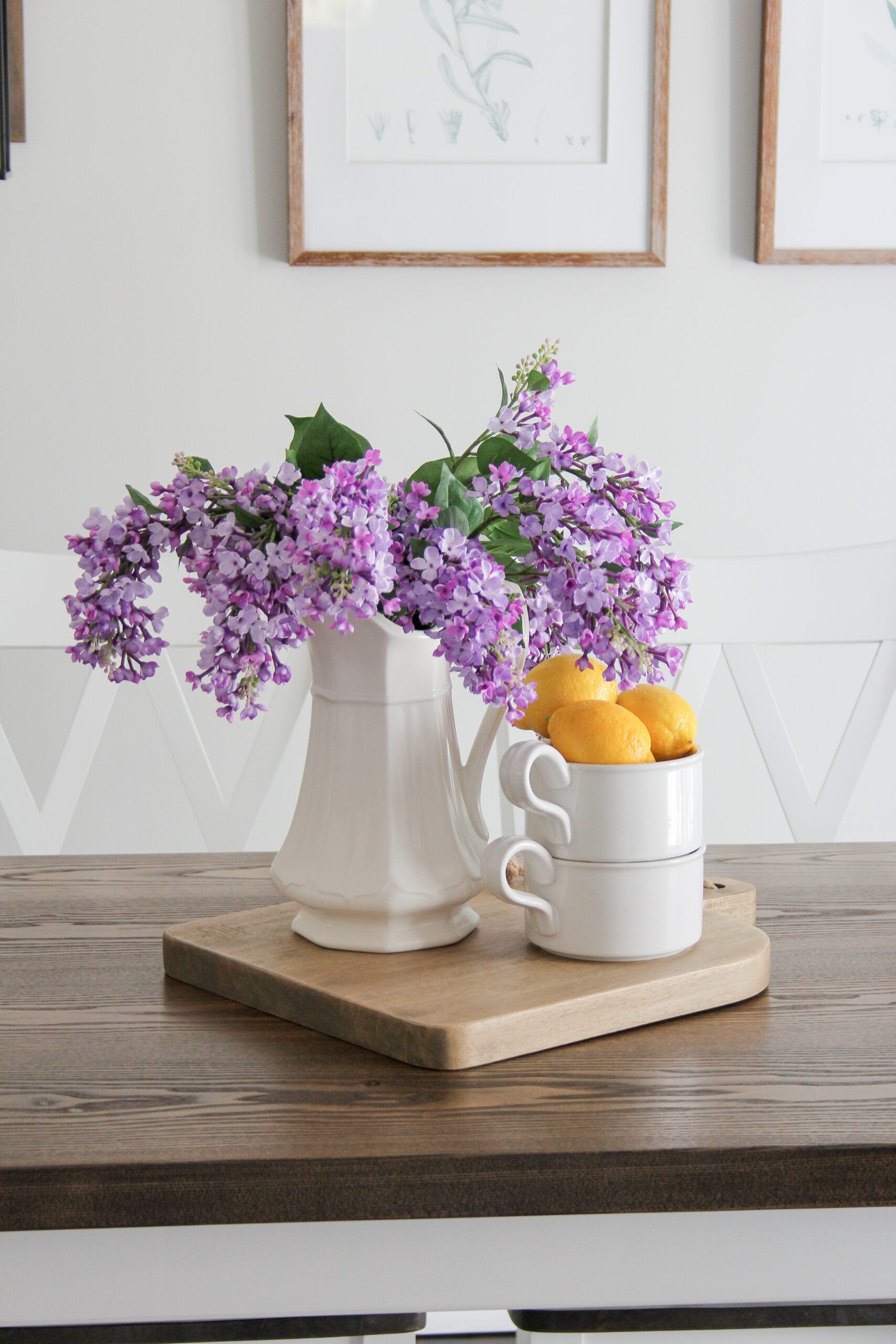 faux lilacs in an ironstone pitcher with porcelain bowls and lemons on a cutting board with a modern farmhouse styled floating shelf. 