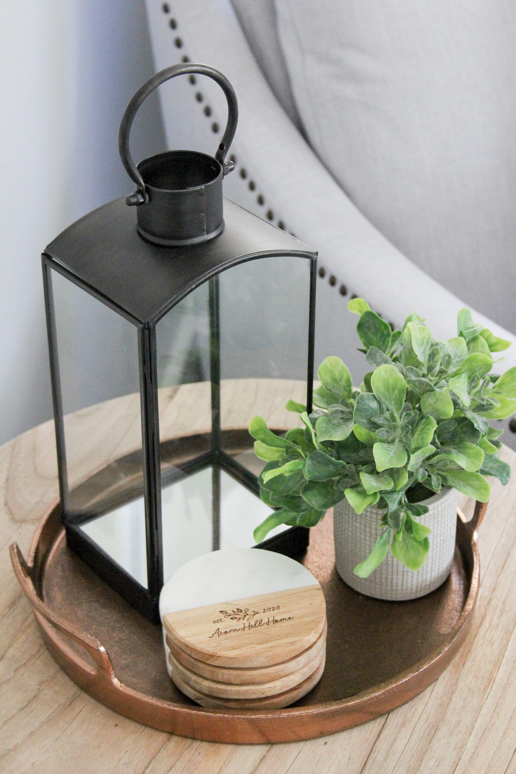 black glass lantern with eucalyptus plant and wooden coasters