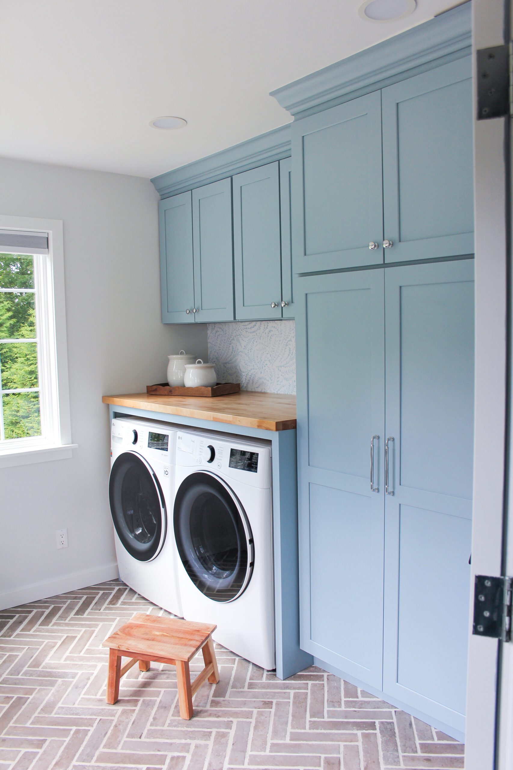 laundry room with blue cabinets, washer dryer, and folding table